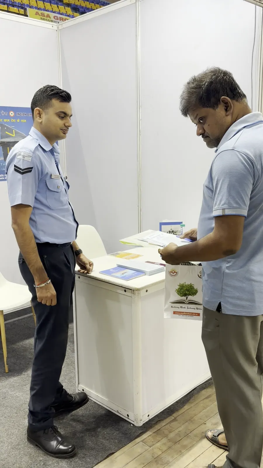 An Indian Air Force officer in uniform speaking with a visitor across a counter.