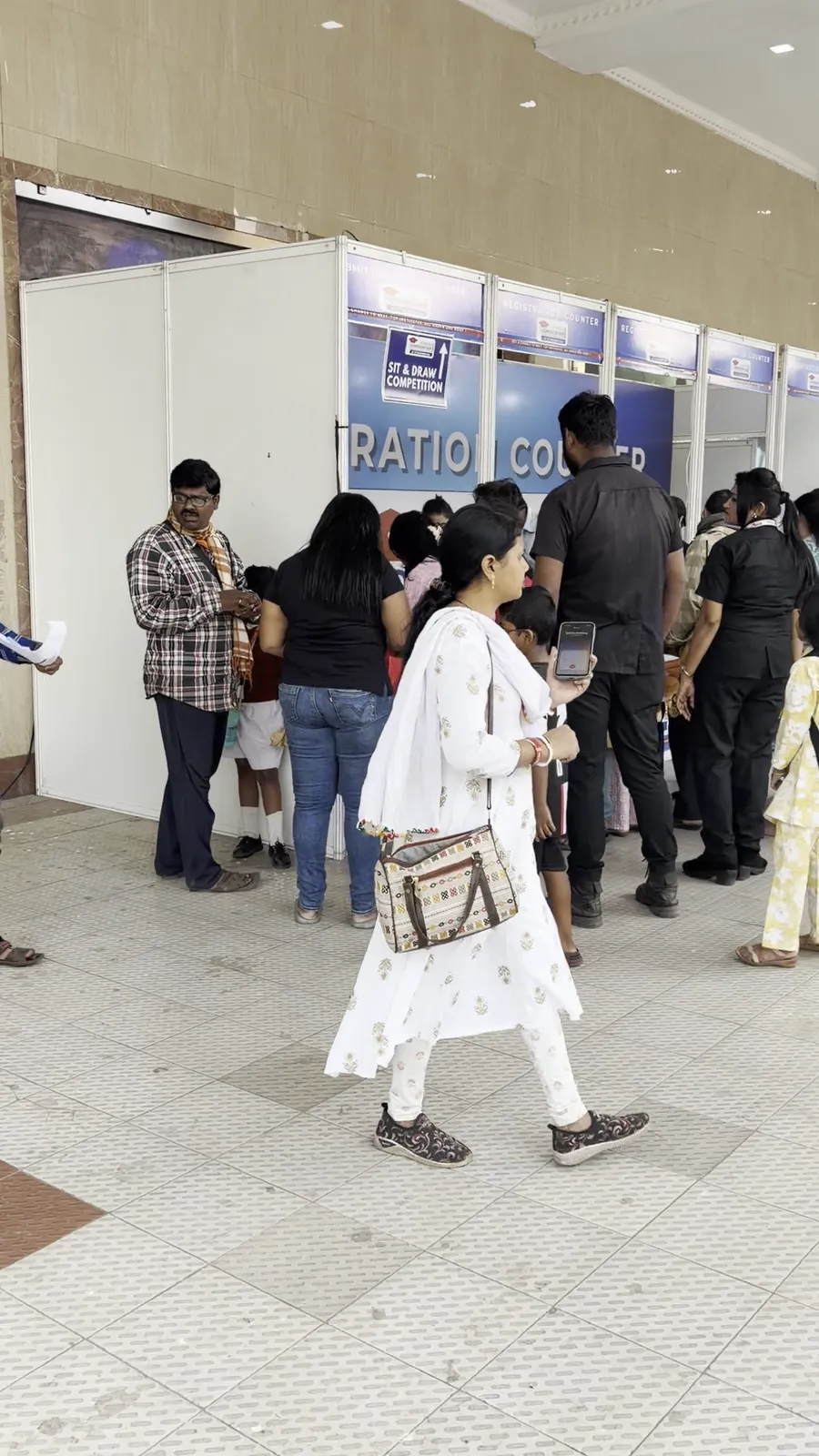 Visitors arriving and queueing along a corridor of registration counters.