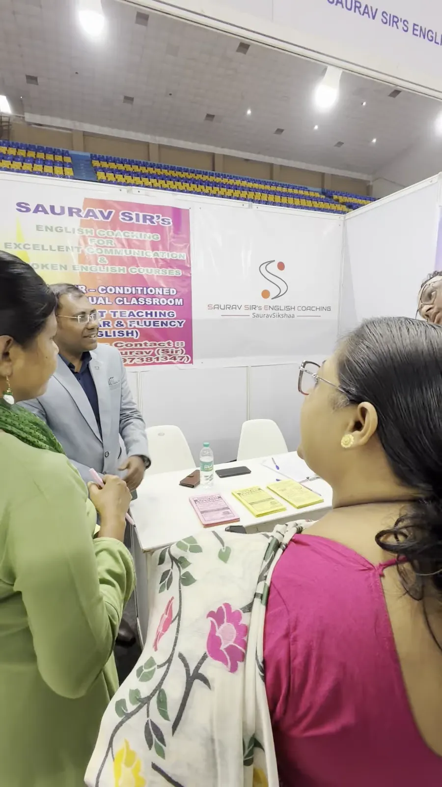 A counsellor speaking with two visitors across an advisory desk.