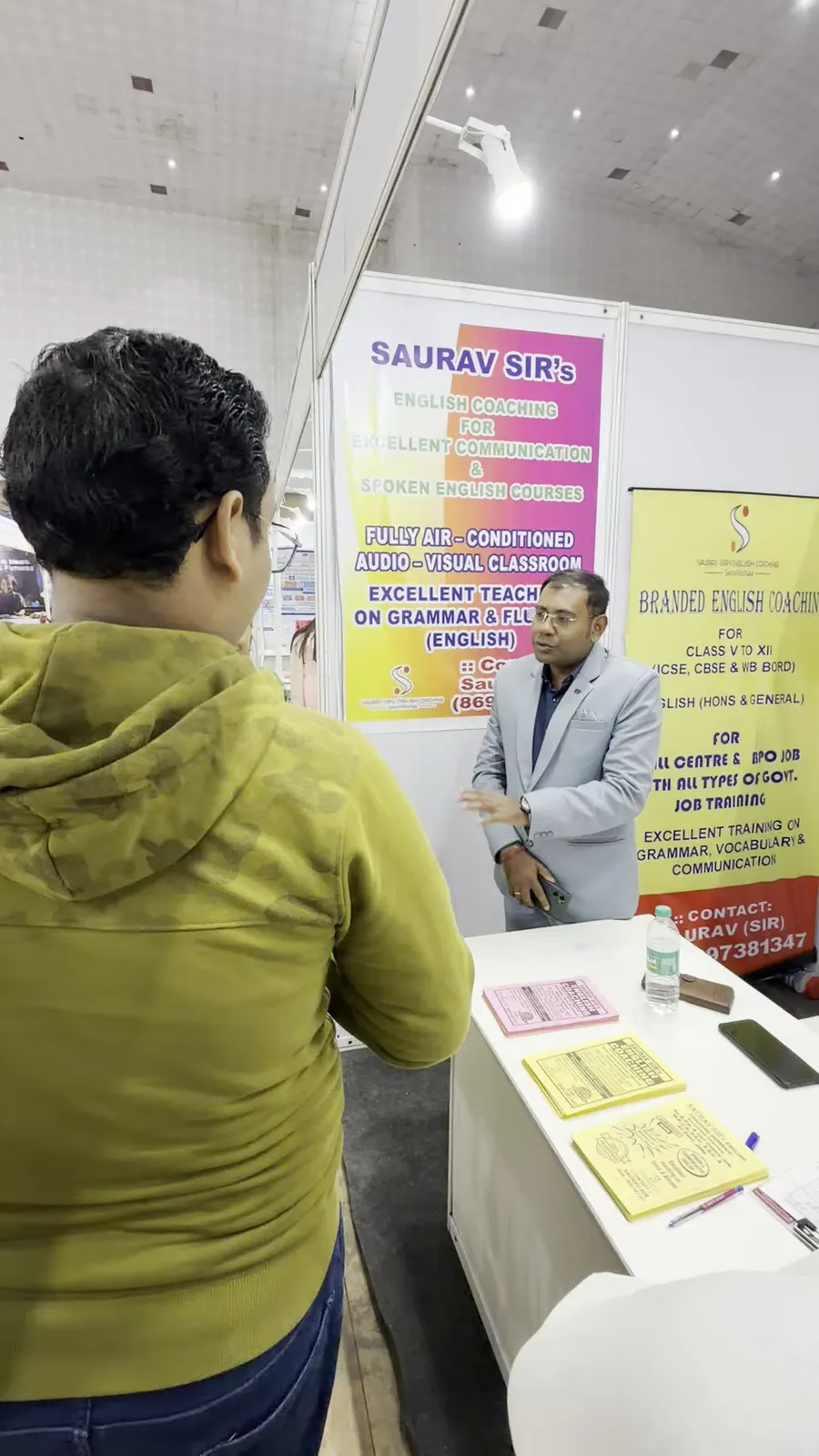 A visitor reading course information with a counsellor at a desk.