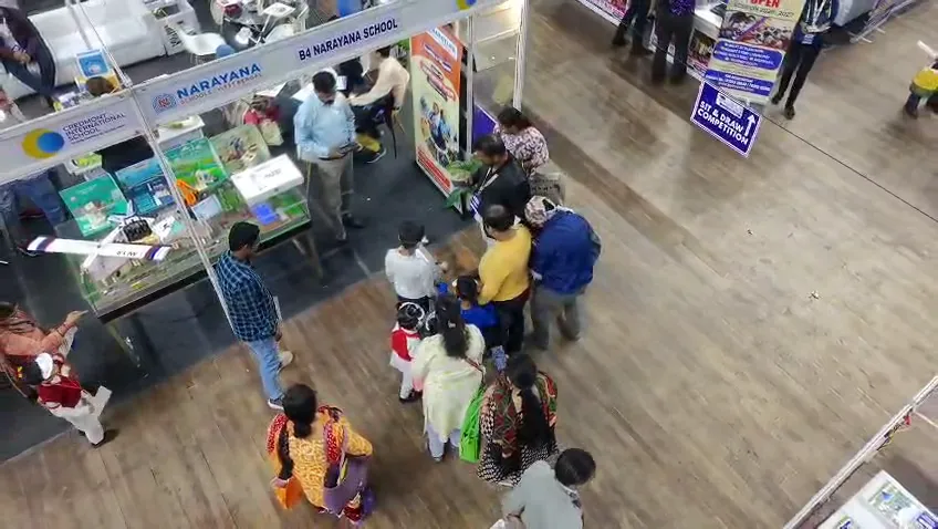 Groups of visitors gathered around several exhibition stalls at once.