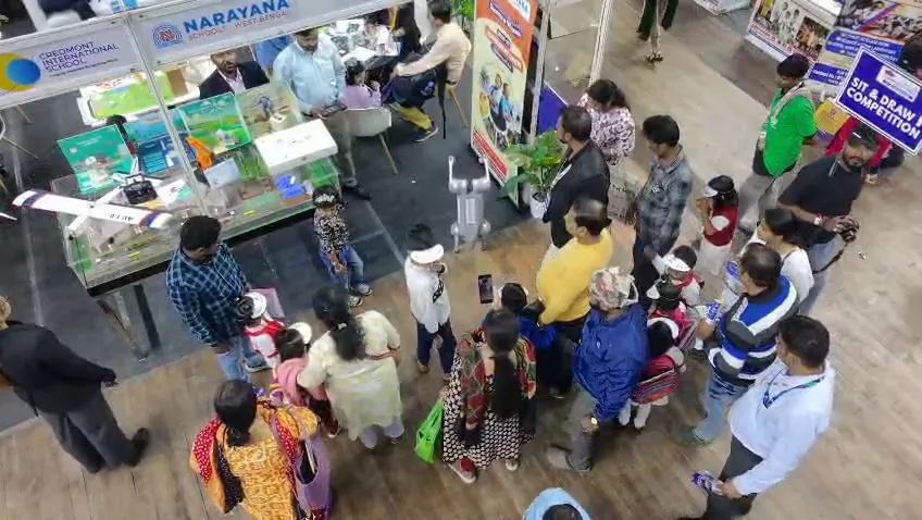 Visitors standing several deep at the counters of adjacent school stalls.