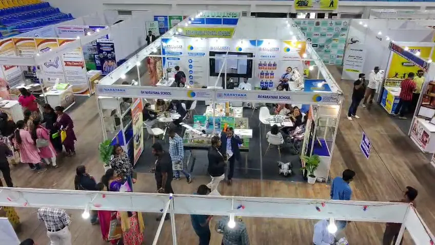 Elevated view of exhibition stalls with visitors browsing at the counters.