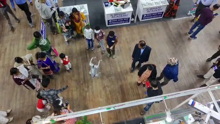 Parents and children walking down an aisle between exhibition stalls.