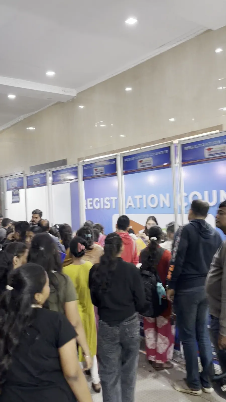 A dense queue of visitors waiting at a row of registration counters.