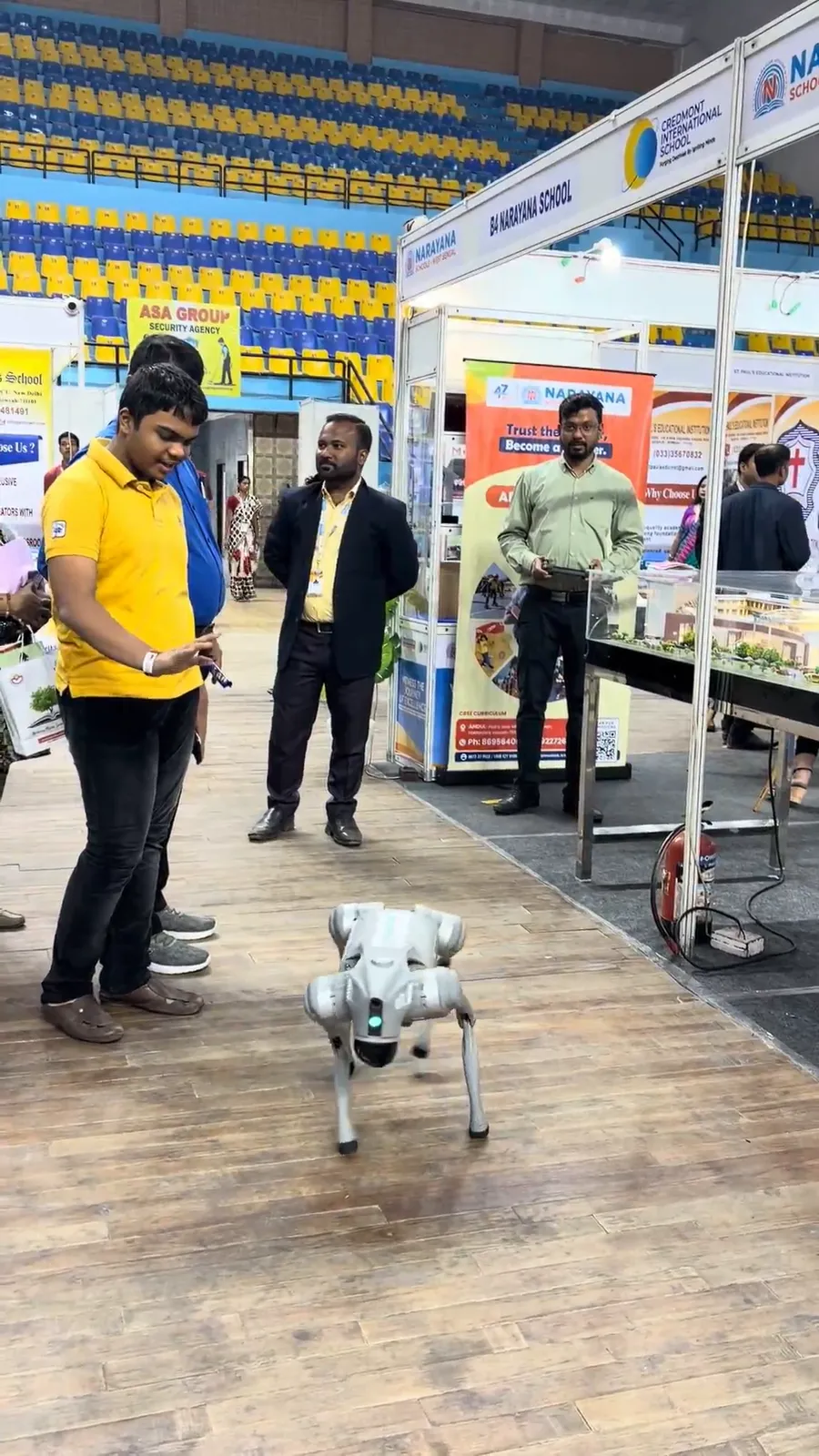 Visitors watching a four legged robot demonstration in an aisle of the hall.