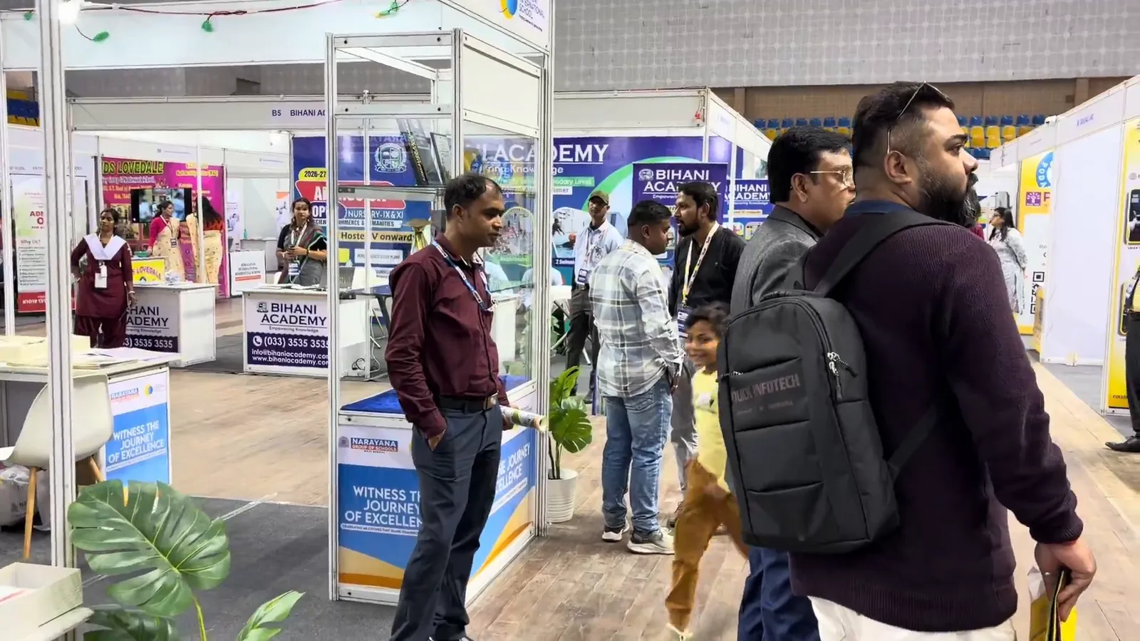 Visitors walking past a run of school stalls, reading the display boards.