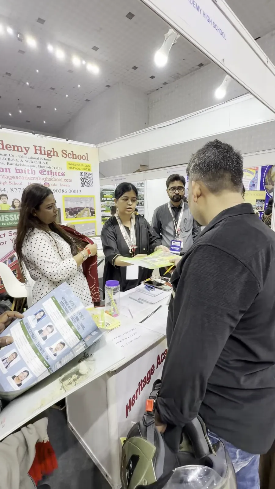 A visitor and a representative looking over printed material at a stall counter.