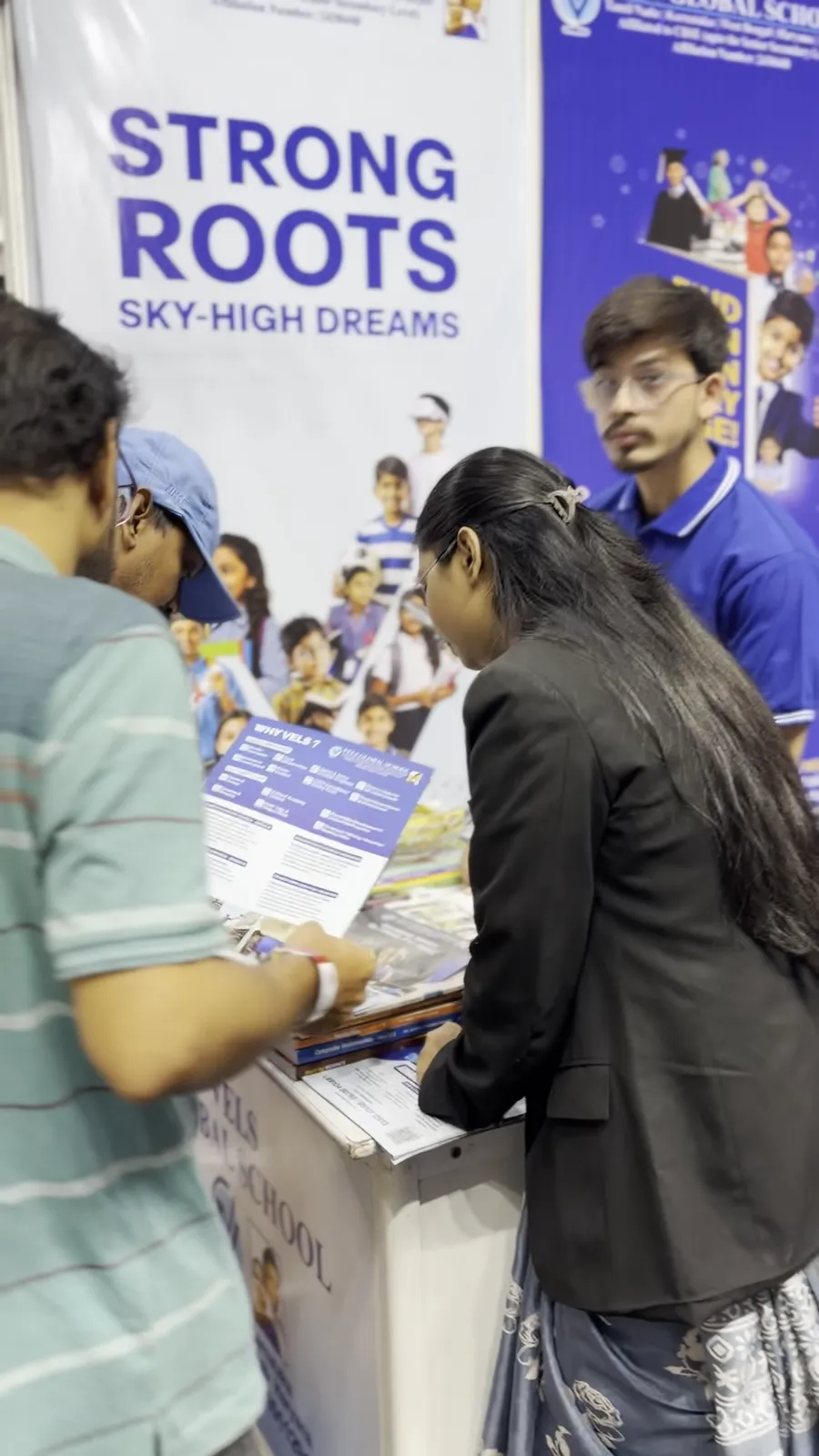 A visitor being handed a leaflet at a school stall counter.